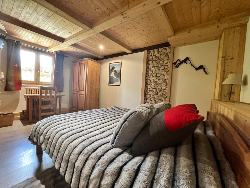 Une chambre au plafond de bois à caissons, avec son grand lit et son mur de pierre apparente