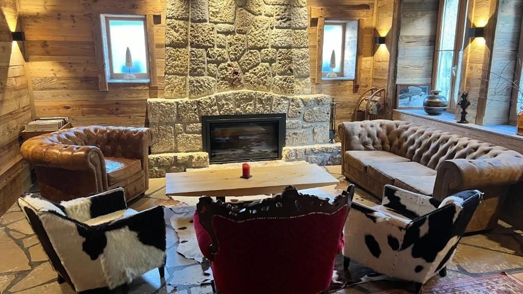 Le salon commun, sa cheminée encastrée dans un mur de pierre, ses canapés de cuir et ses peaux de vache