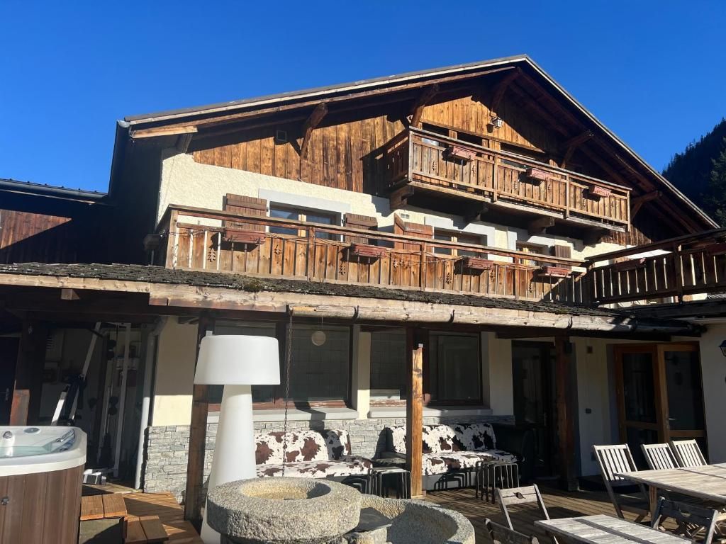 La terrasse de la maison en été, avec ses transats, son mobilier de jardin et le bain à remous à l’angle