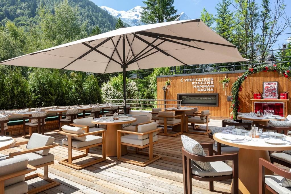 La terrasse du restaurant sous ses parasols, ses tables dressées et le versant boisé derrière