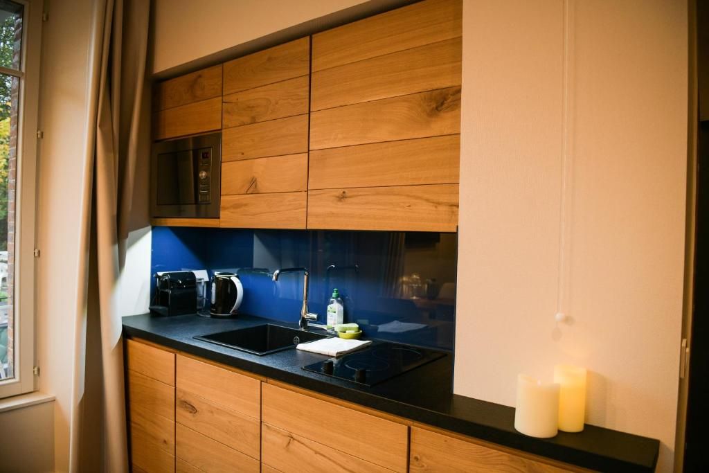 La kitchenette de bois d’un logement, avec ses plaques, son évier et ses rangements hauts