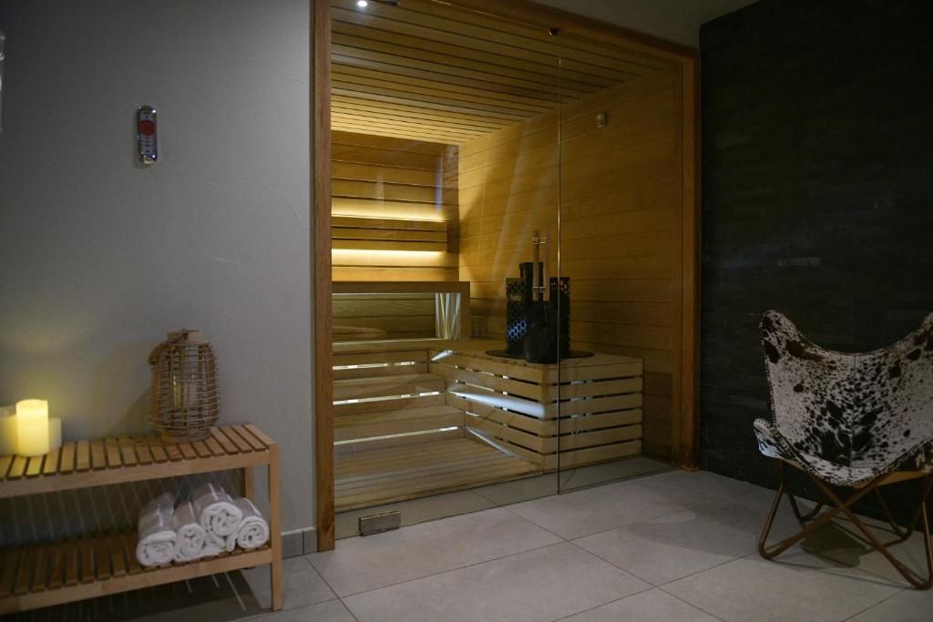 Le sauna de bois clair vu depuis la salle de repos, avec ses serviettes pliées et sa bougie allumée