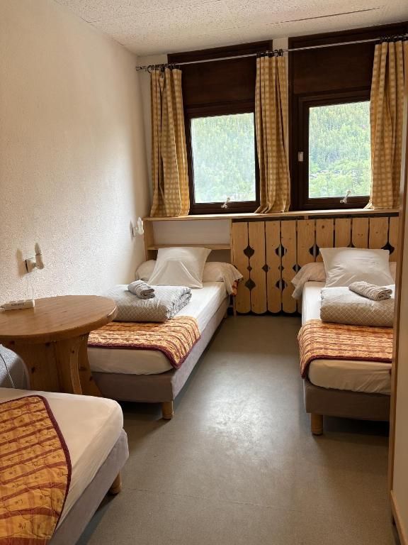 Une chambre privative à deux lits simples, avec sa table ronde et ses fenêtres sur la vallée