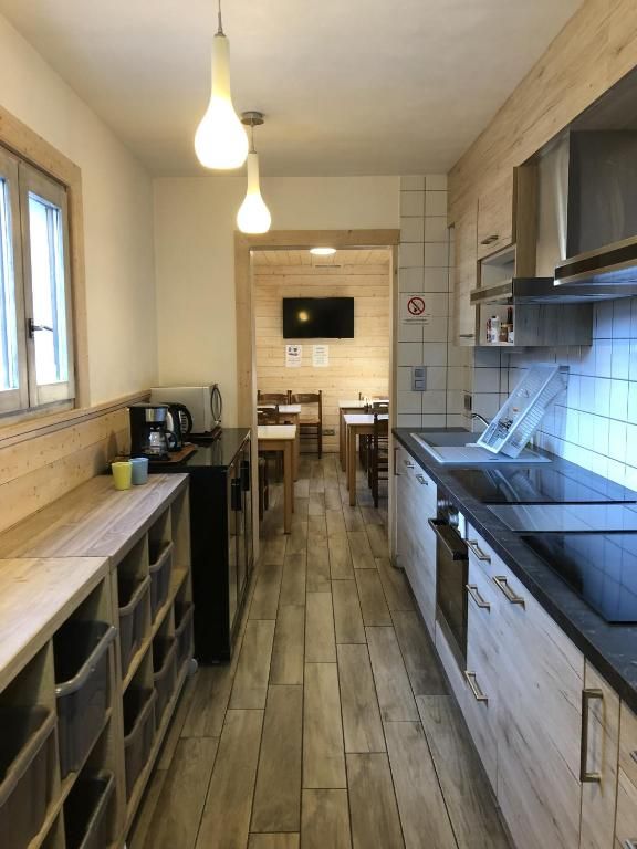La cuisine commune, avec son plan de travail, ses plaques et le coin repas au fond