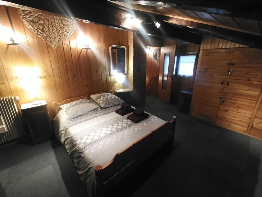 Une chambre entièrement lambrissée de bois, avec son lit double et sa lampe de chevet allumée