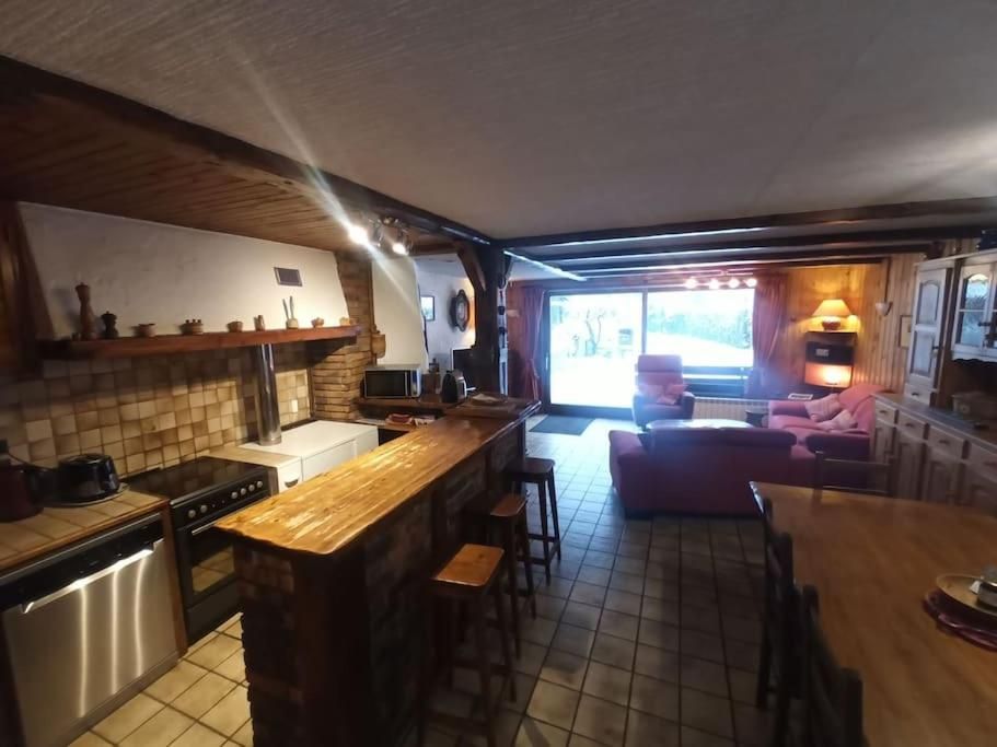 La cuisine et son bar de bois massif, ouverts sur le séjour et sur la baie vitrée du fond
