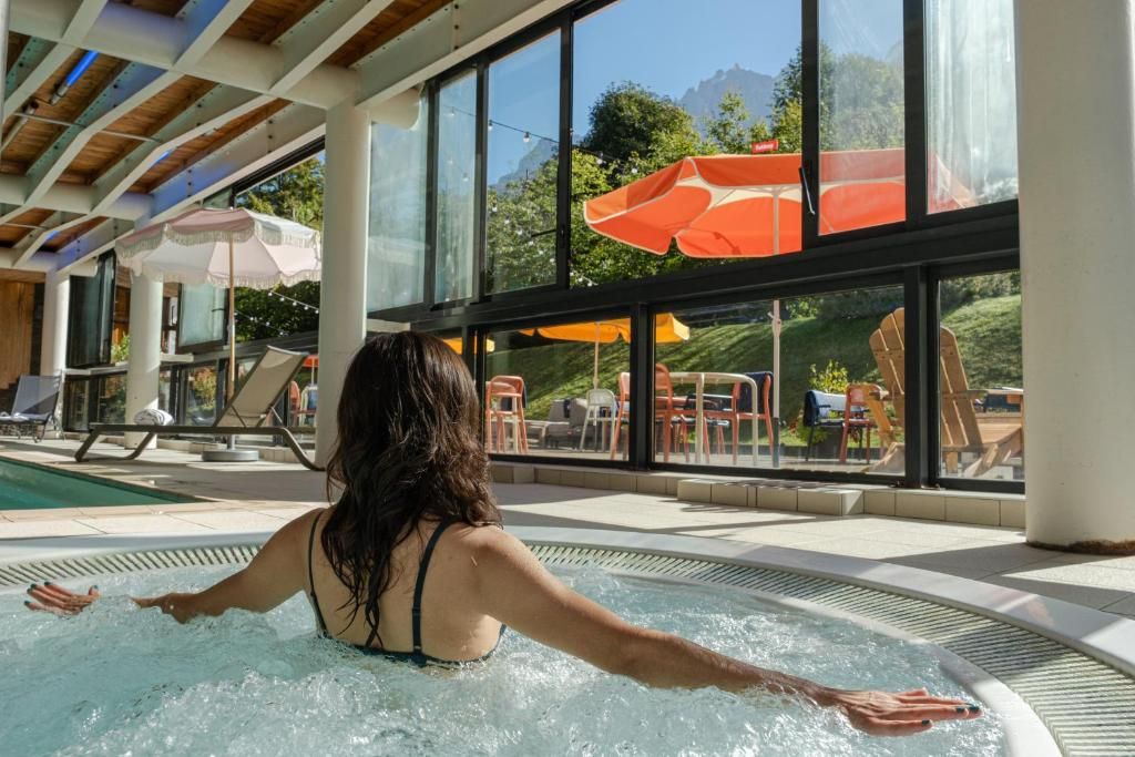 La piscine intérieure chauffée sous sa charpente blanche, ouverte par une paroi vitrée sur la terrasse