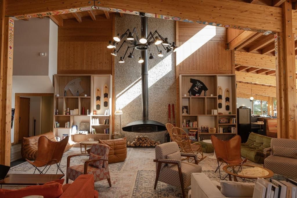 Le salon commun sous charpente, avec sa cheminée suspendue centrale, ses fauteuils de cuir et ses tapis