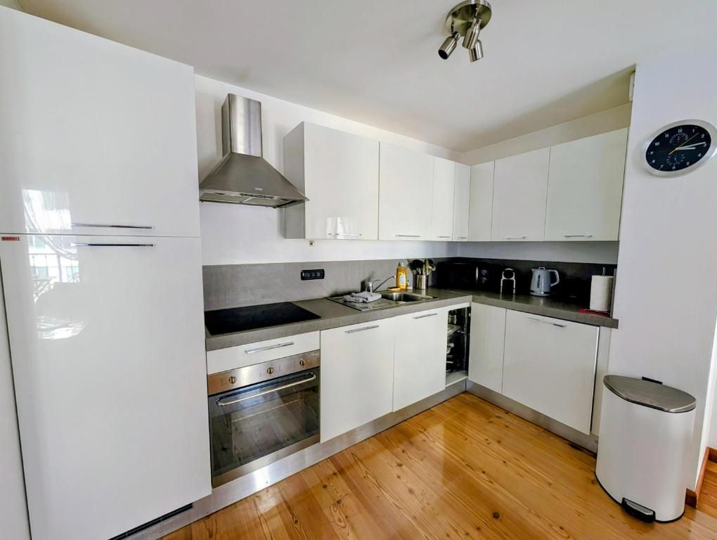 La cuisine blanche entièrement équipée, avec four, hotte et plaque à induction