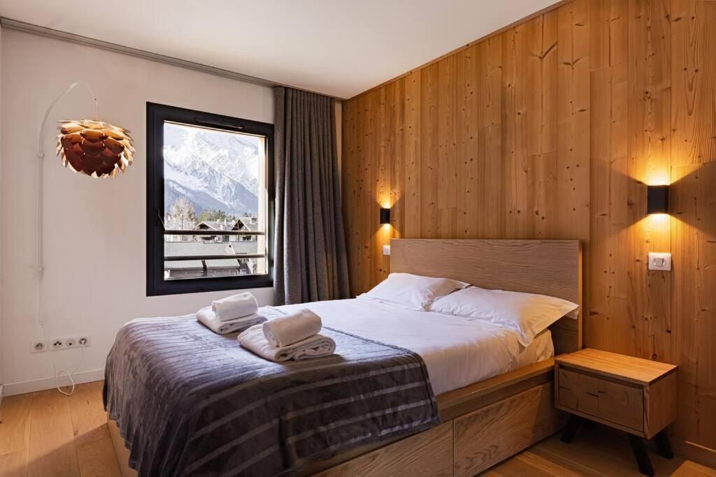 Une chambre lambrissée de bois clair, avec son grand lit et sa fenêtre sur le versant