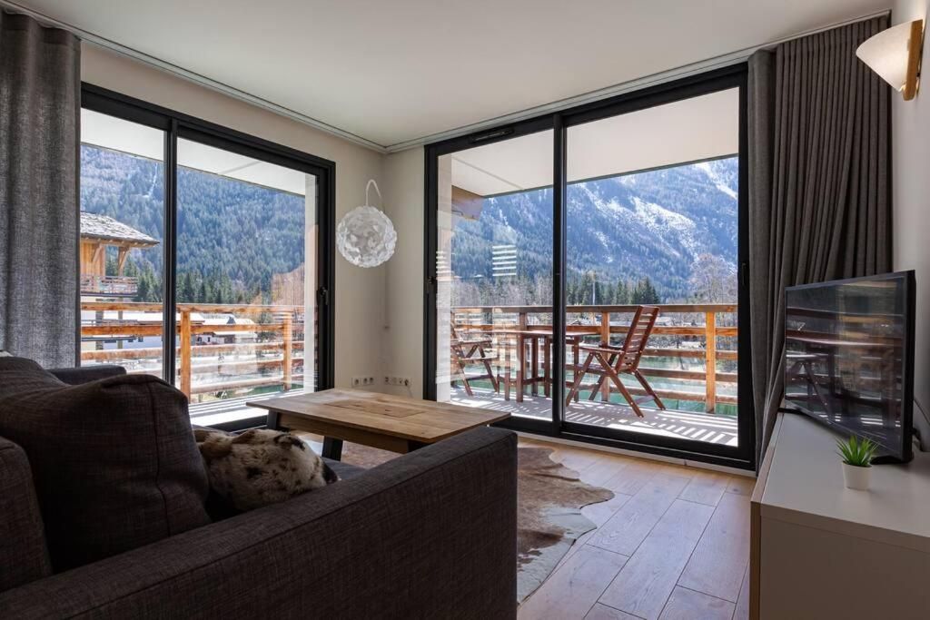 Le séjour de l’appartement, avec son canapé d’angle et sa baie vitrée ouverte sur le balcon et la montagne