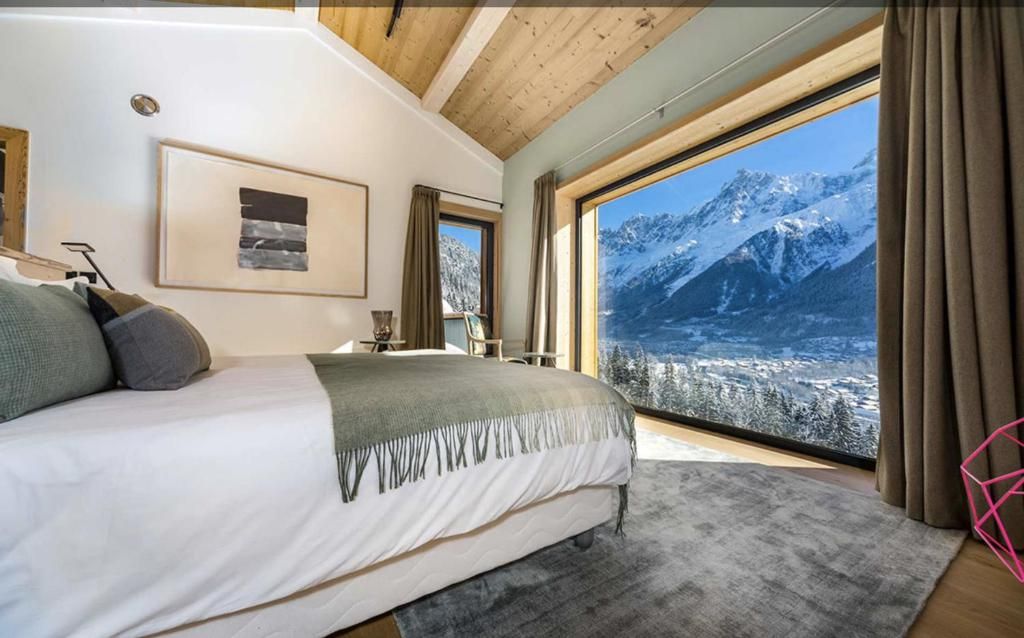 Une chambre dont la paroi entière est vitrée sur la chaîne enneigée, avec son grand lit face à la vue