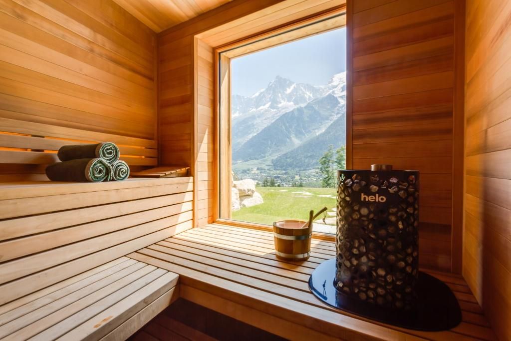 Le sauna de bois clair, avec son poêle et sa fenêtre ouverte sur les sommets enneigés