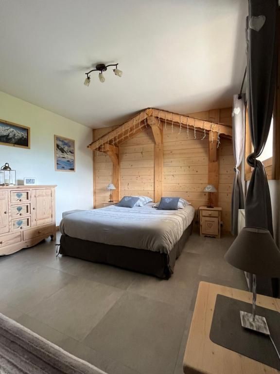 La chambre lambrissée sous sa charpente apparente, avec son grand lit et sa commode de bois clair