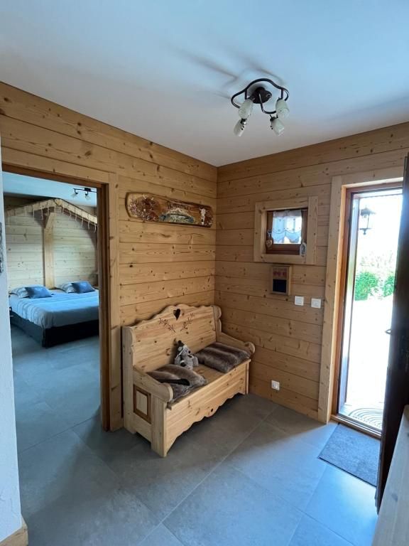 L’entrée de bois avec son banc coffre, ouverte d’un côté sur la chambre et de l’autre sur le jardin