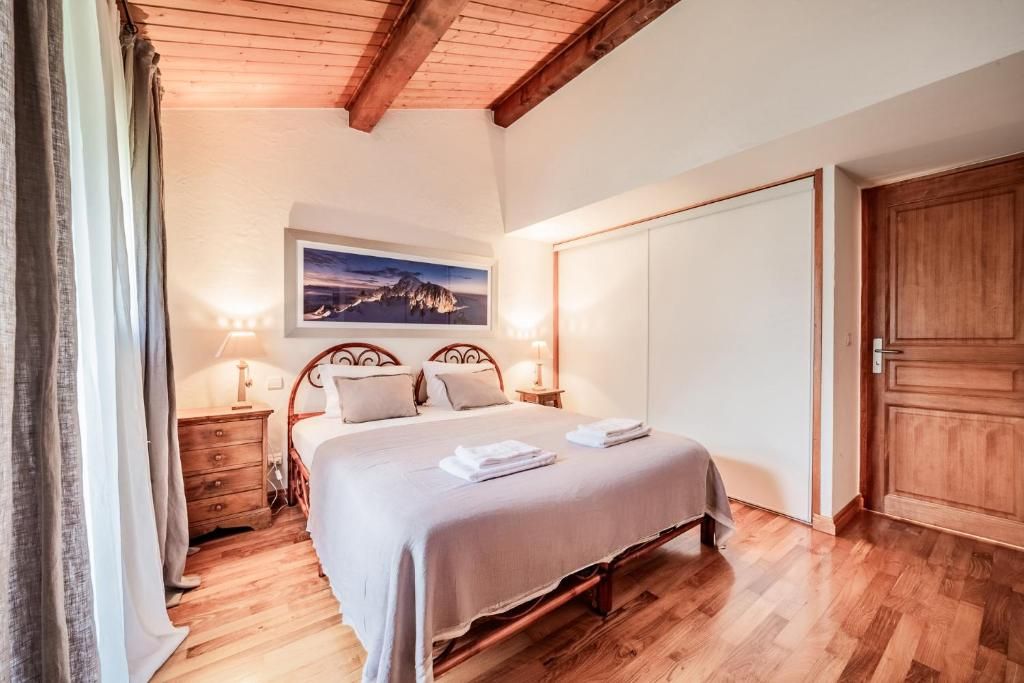 Une chambre sous charpente apparente, avec son grand lit et son parquet clair