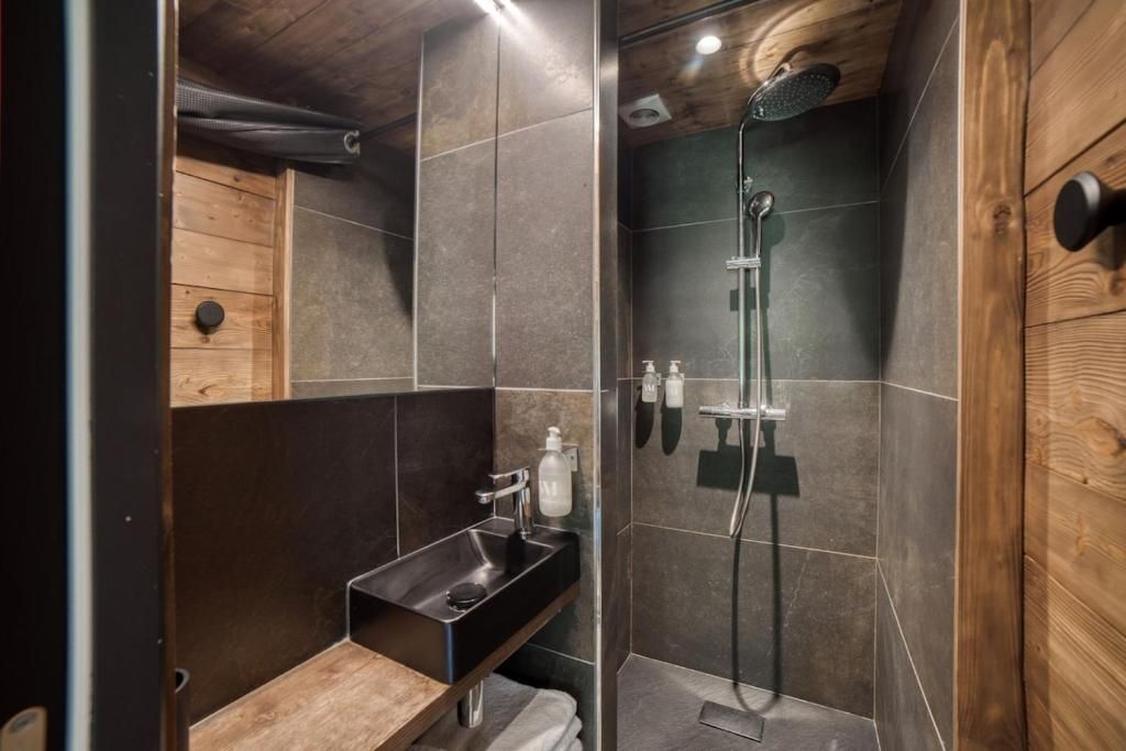 Une des deux salles d’eau, en bois sombre et pierre, avec douche à l’italienne