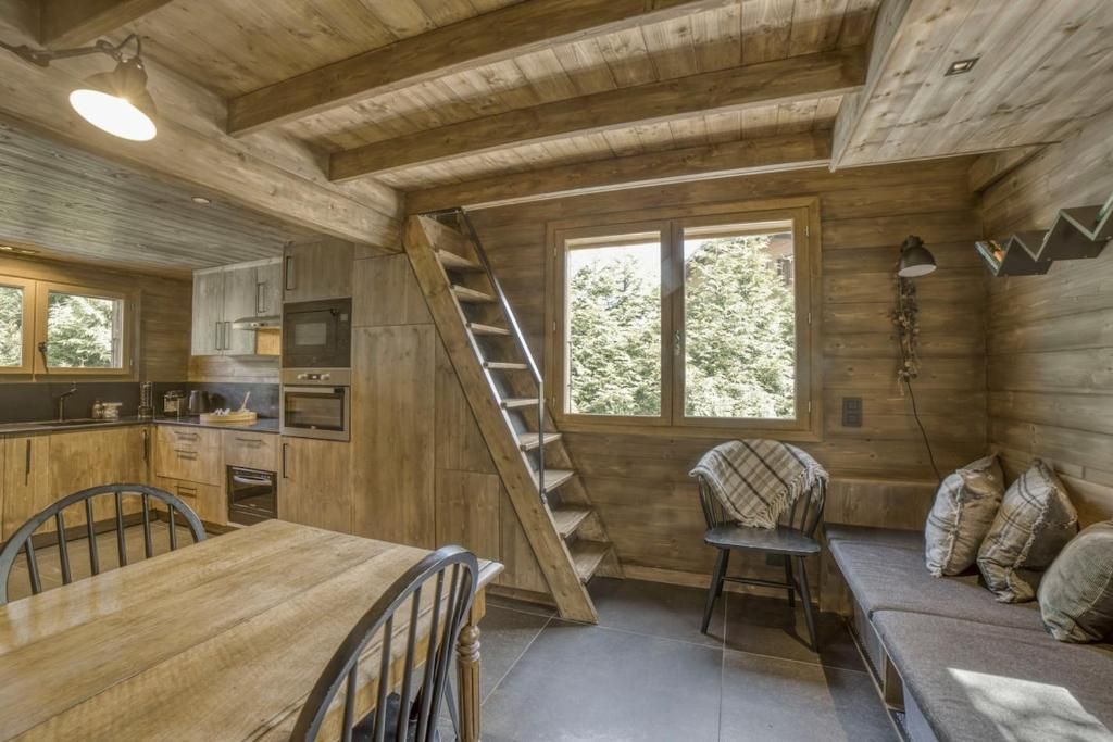 Le séjour lambrissé, avec la table, le canapé et l’échelle de meunier qui monte au couchage de l’étage
