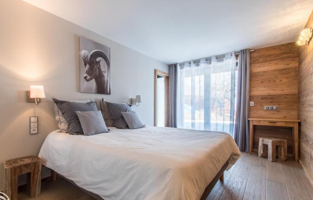 La chambre, son grand lit, ses appliques et sa porte-fenêtre ouverte sur la terrasse