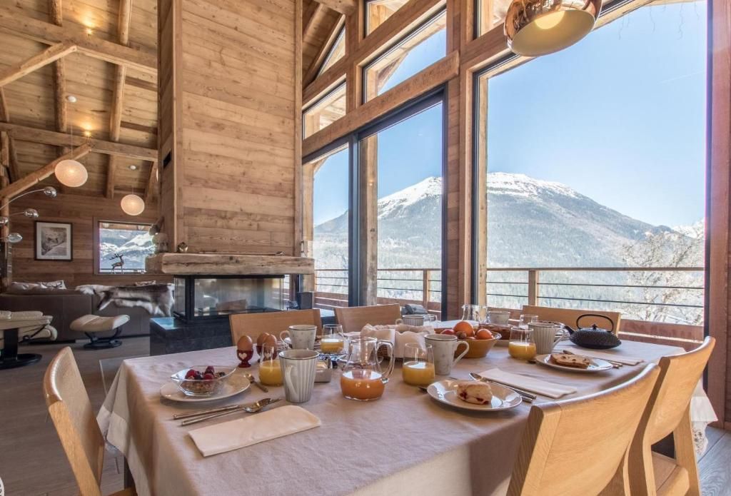 La table du petit-déjeuner dressée devant la baie vitrée, avec le sommet enneigé qui occupe toute la fenêtre