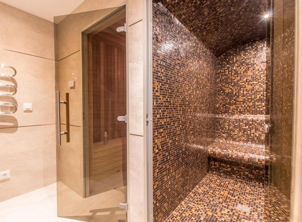 La porte de bois du sauna, ouverte sur la cabine, à côté du hammam en mosaïque sombre