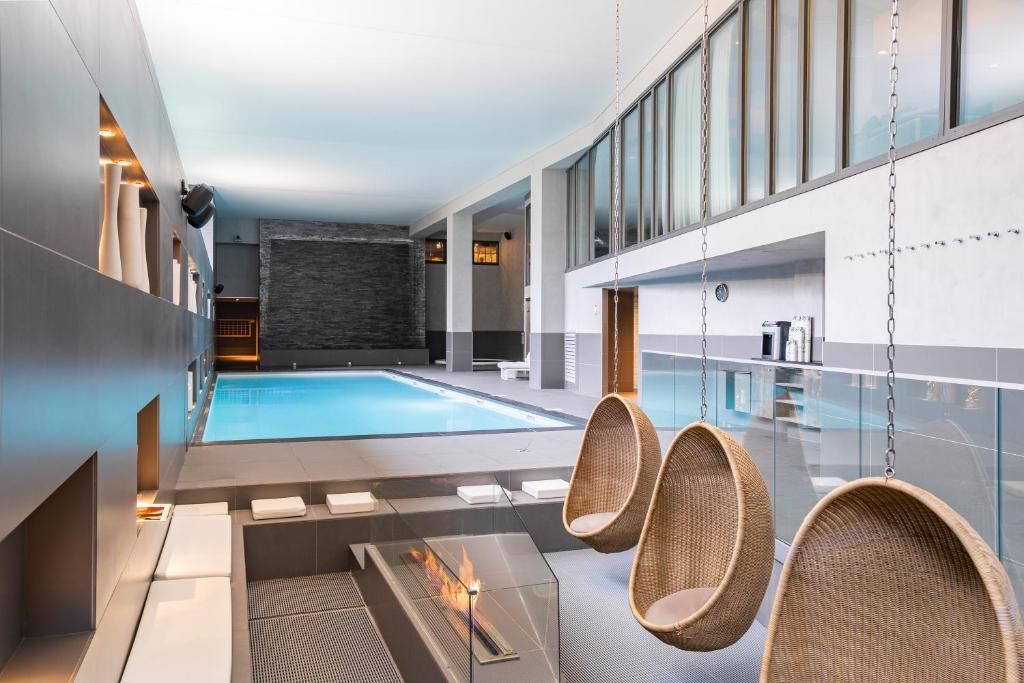 L’espace de détente du spa, ses fauteuils-cocons suspendus et son foyer ouvert, devant la baie vitrée