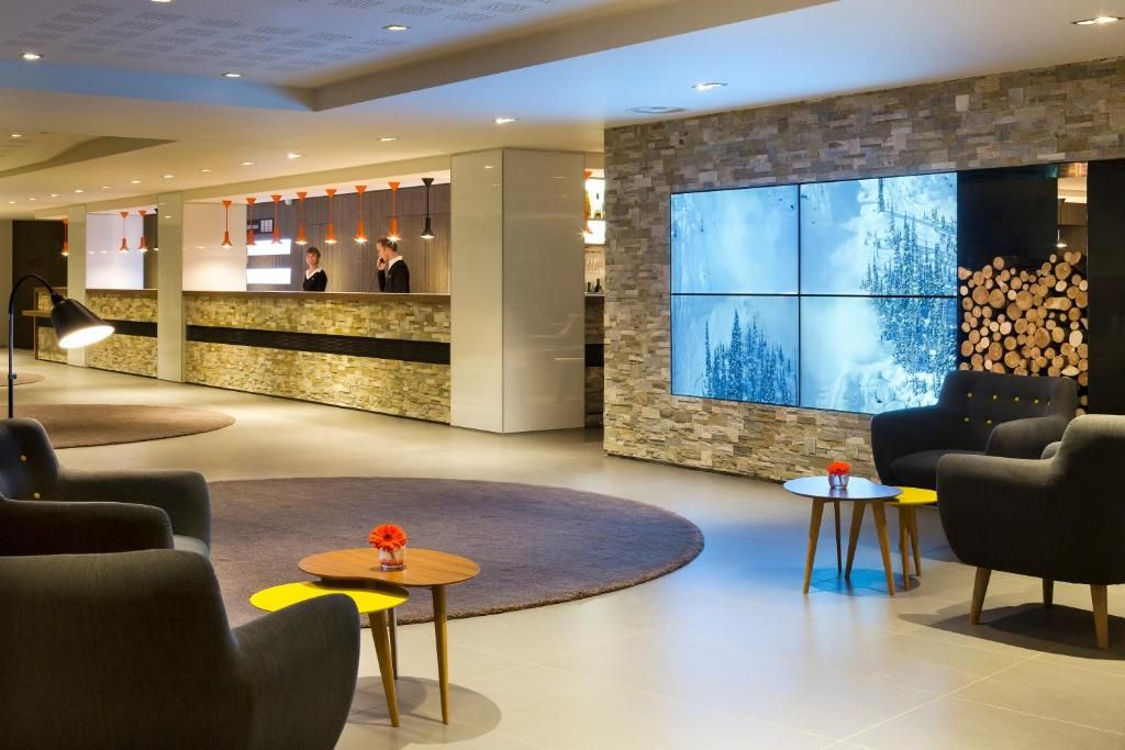 Le hall de l’hôtel, ses fauteuils bas, son mur de pierre et sa réserve de bûches