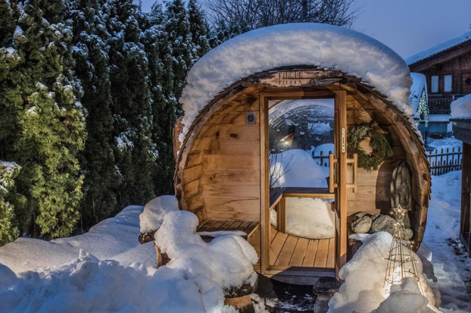 Le sauna extérieur en forme de tonneau, sous la neige, au crépuscule