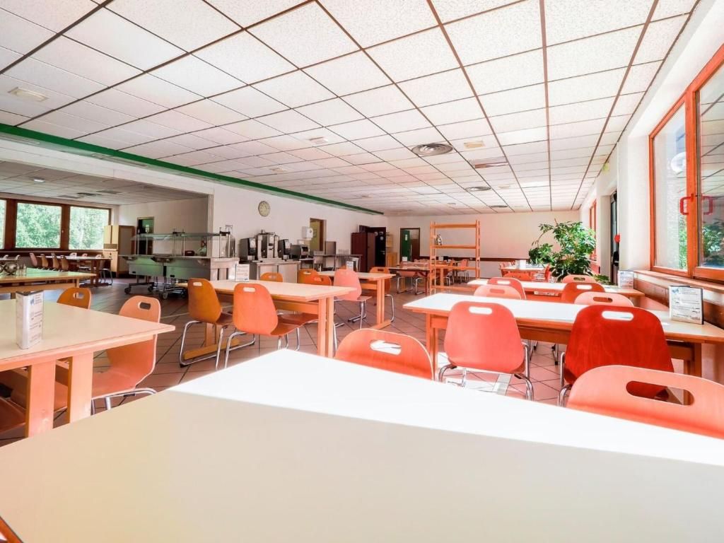 La salle à manger commune, avec ses longues tables blanches et ses chaises orange