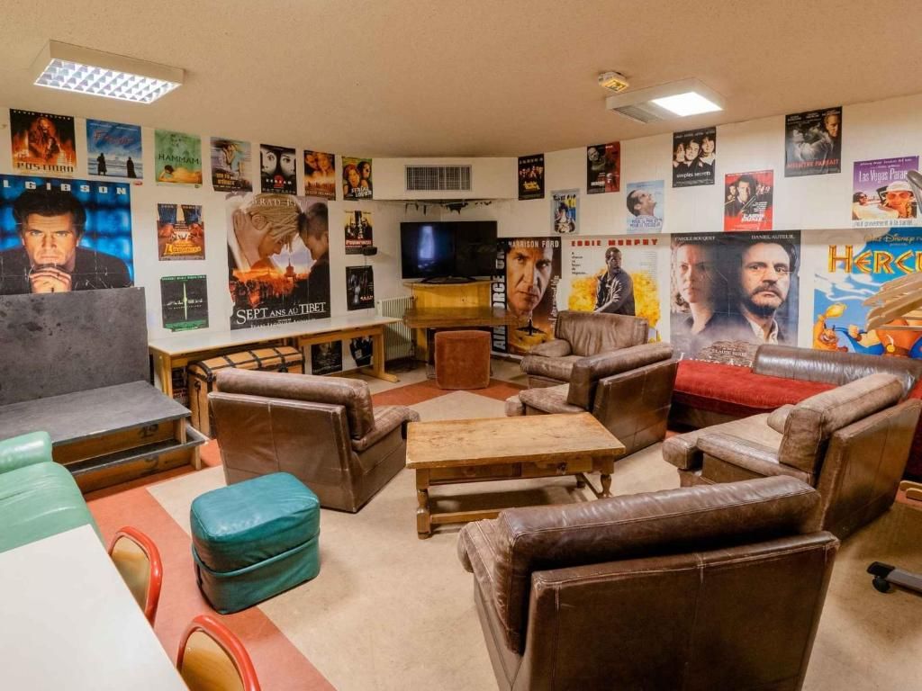 Le salon commun, ses canapés de cuir, ses poufs et ses affiches de cinéma au mur