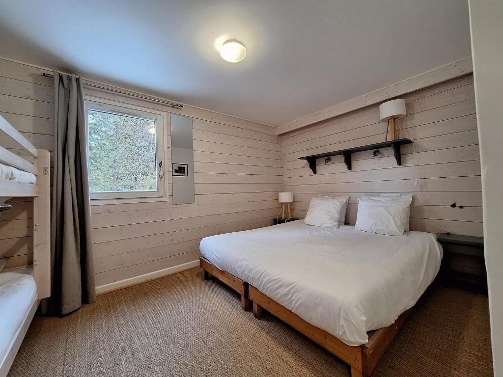Une chambre sous pente, son très grand lit et sa fenêtre basse donnant sur la neige