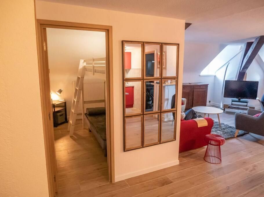 Le salon vu depuis la porte vitrée d’une chambre à lits superposés, avec le canapé rouge et la télévision