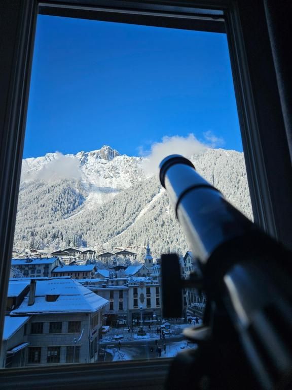 Une lunette astronomique posée devant la fenêtre de l’appartement, face au versant enneigé et aux toits du bourg