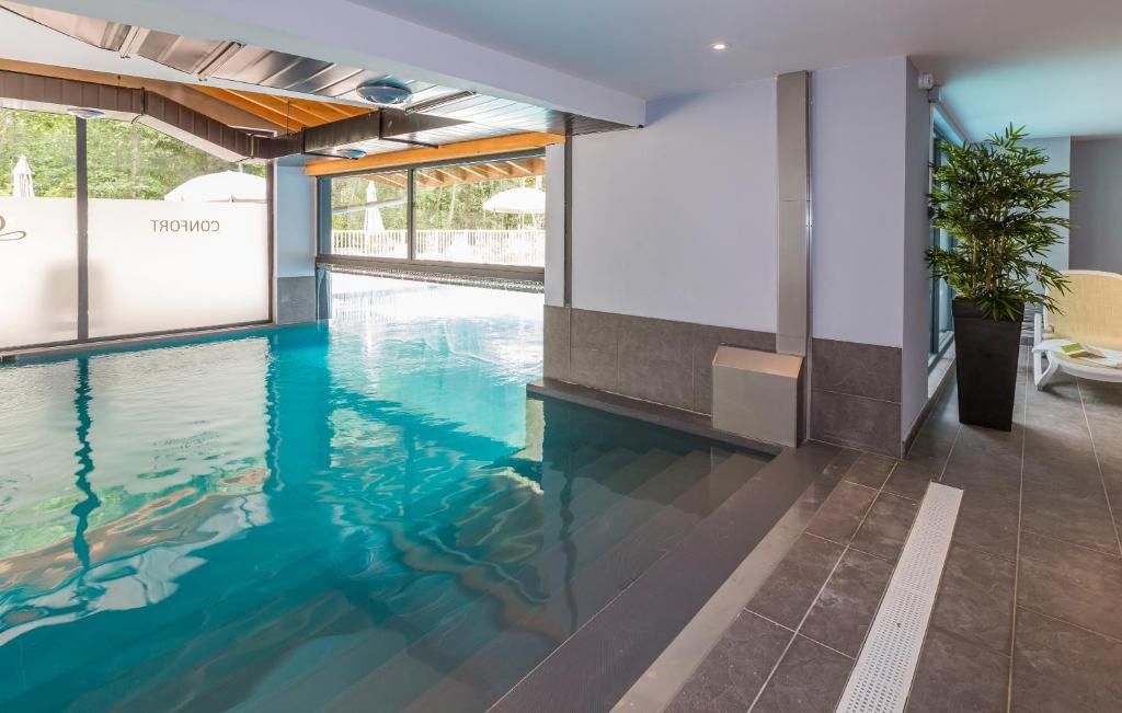 La piscine intérieure sous son plafond de bois, ouverte par une baie vitrée sur le jardin