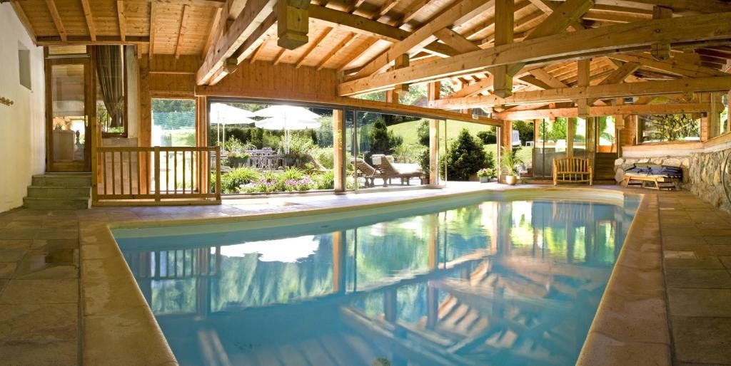 La piscine intérieure sous sa charpente de bois, ouverte par une paroi vitrée sur le jardin