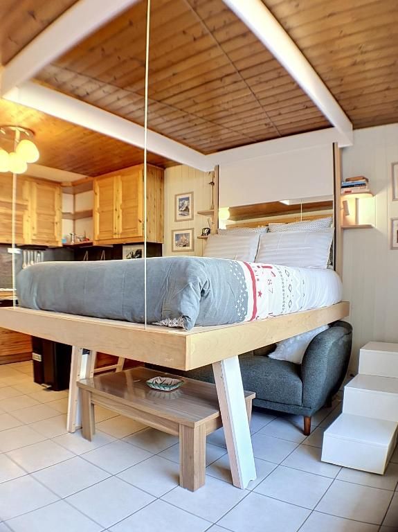 Le couchage surélevé de bois clair, monté au-dessus du canapé et accessible par une échelle