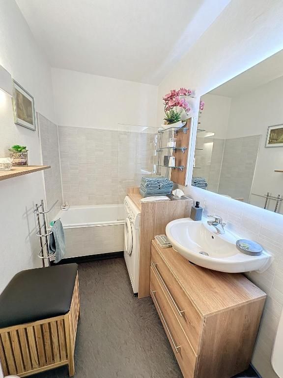 La salle de bains, avec sa baignoire, son lave-linge encastré et son grand miroir