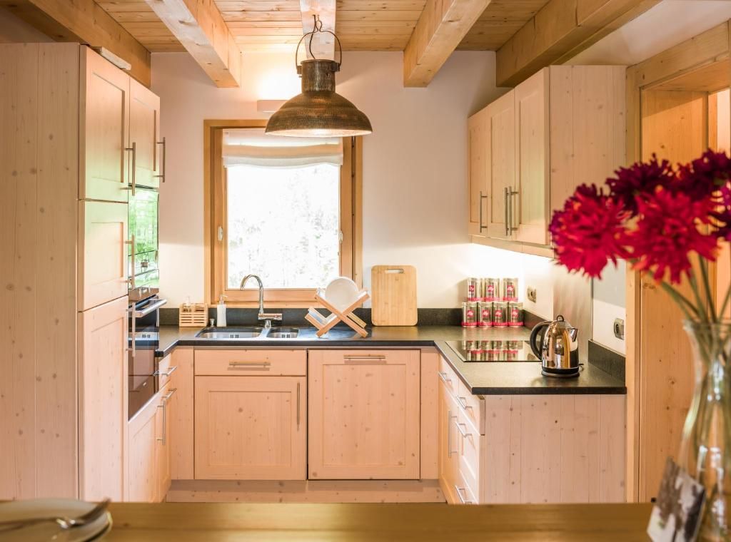 La cuisine équipée du chalet, en bois clair, ouverte sur la fenêtre du jardin