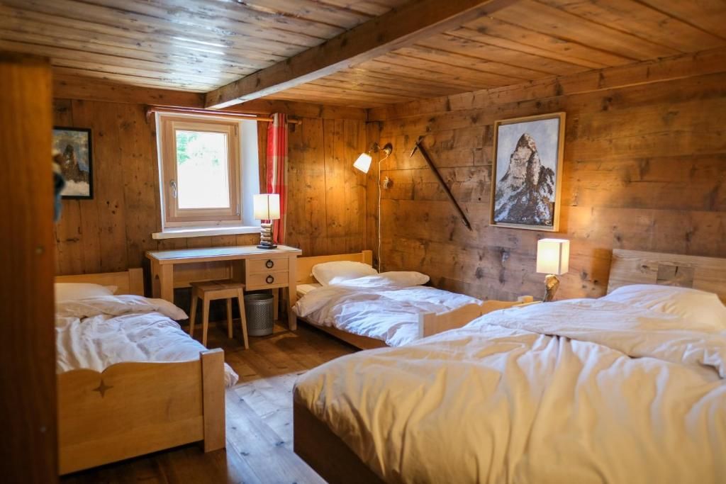 La chambre familiale entièrement lambrissée de vieux bois, avec ses plusieurs lits et sa petite fenêtre