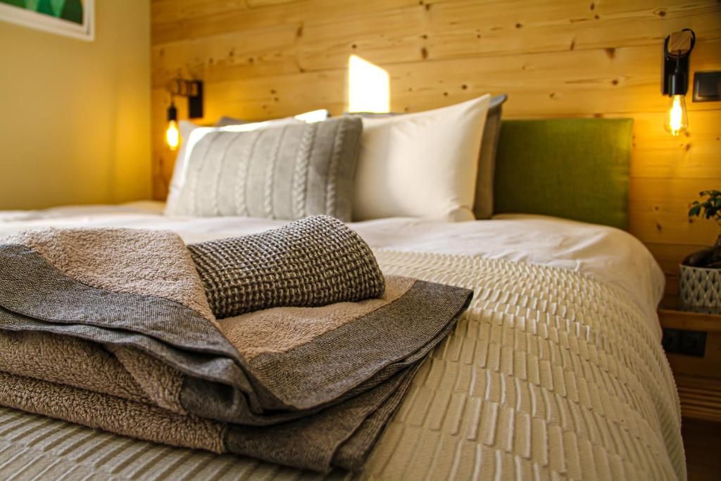 Une chambre avec sa tête de lit de bois clair et ses appliques, sous une paroi de sapin
