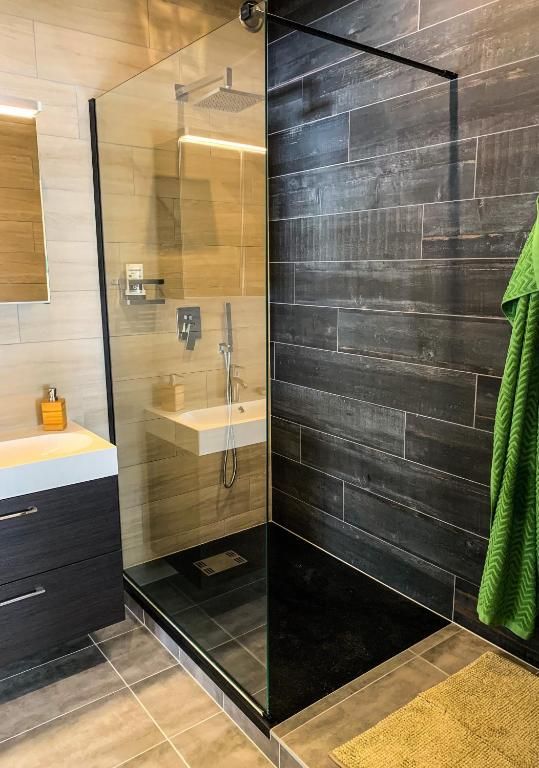 La salle de bains, avec sa large douche à l’italienne et son mur de carreaux sombres