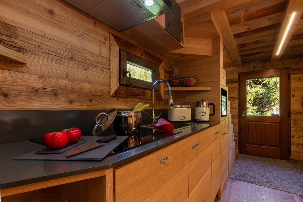 La cuisine du mazot en bois clair, avec ses plaques, son plan de travail et la porte ouverte sur le jardin