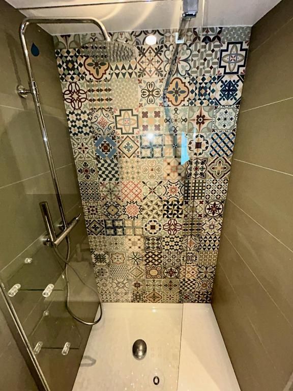 La douche à l’italienne et son mur de carreaux de ciment à motifs, entre deux parois vert d’eau