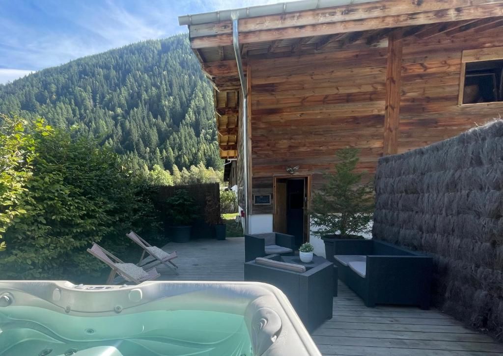 Le bain à remous en plein air sur la terrasse de bois, abrité par une palissade, avec la forêt derrière