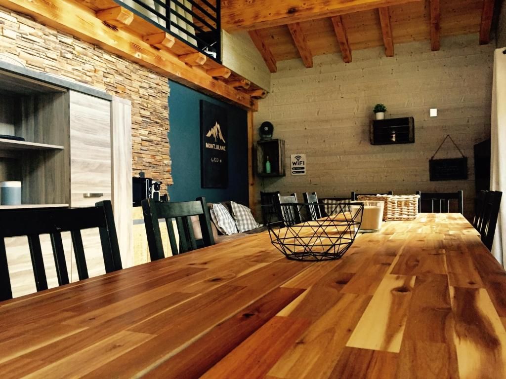 Le séjour du chalet avec sa grande table de bois, la cheminée et la cuisine ouverte au fond