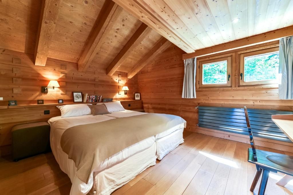 Une chambre sous charpente, avec son grand lit, ses appliques et ses deux fenêtres