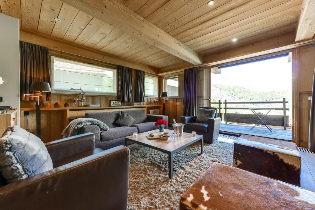 Le séjour lambrissé, ses canapés de cuir, son tapis de laine et sa baie ouverte sur le balcon