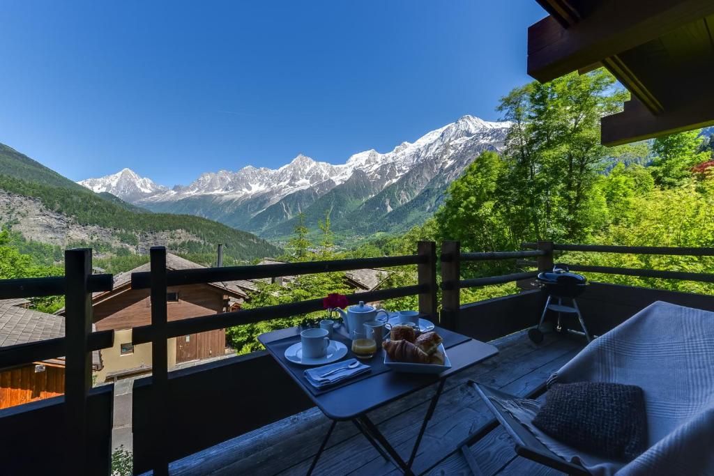 La terrasse et son bain à remous encastré, avec une table dressée et la chaîne enneigée au fond