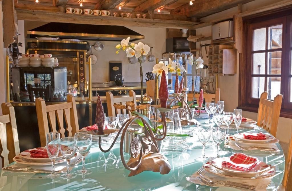 La salle à manger dressée, avec sa longue table, ses verres et ses lustres sous le plafond de bois