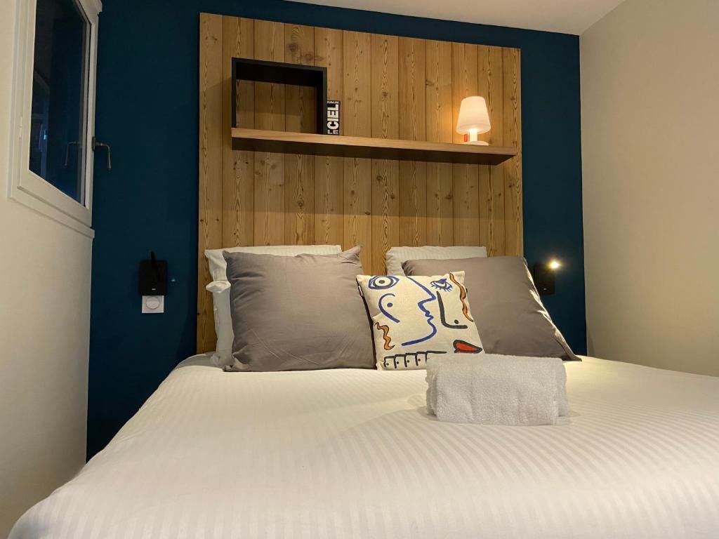 Une chambre à mur bleu sombre et tête de lit de bois, éclairée par deux appliques